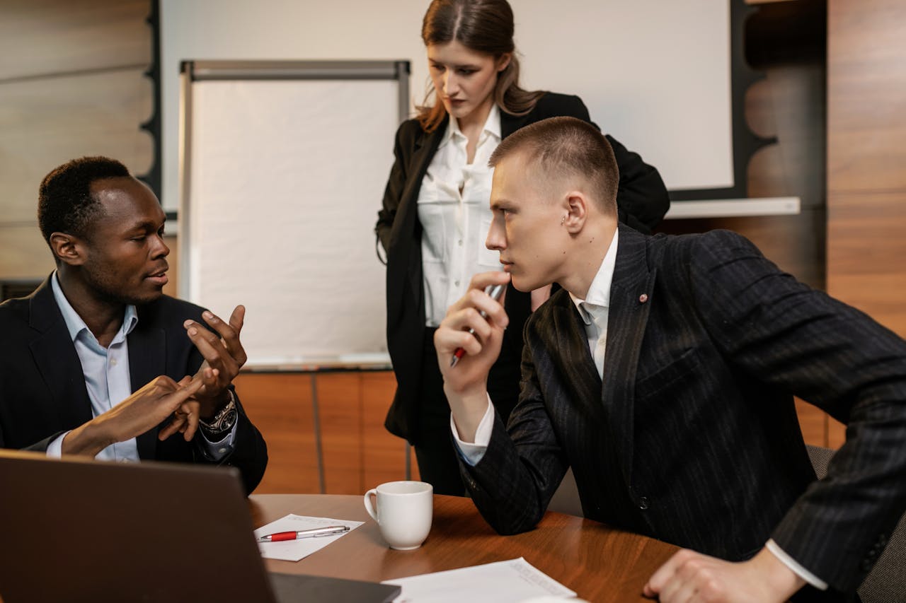 Diverse colleagues in active discussion around a conference table in a modern office setting.